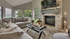 Un salón espacioso con un ventanal grande, una chimenea y un área de estar confortable.