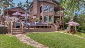 Una amplia casa de madera con varias terrazas, mobiliario exterior y un camino de piedra.