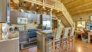 A spacious kitchen with modern appliances, a wooden staircase, and a cozy seating area with a fireplace. - Ski-in/ski-out Telluride Home w/ Deck & Hot Tub! (Telluride)
