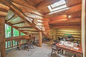 L’intérieur d’une cabane en rondins, avec une table à manger en bois, des chaises, un canapé et une cheminée.