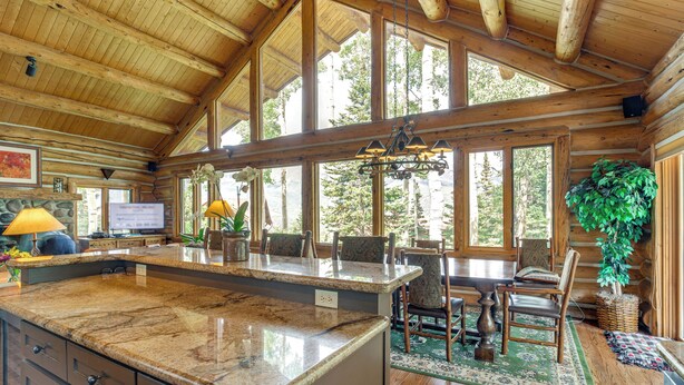 A spacious kitchen with a granite countertop, wooden ceiling, and large windows offering a view of the forest. - Ski-in/ski-out Telluride Home w/ Deck & Hot Tub! (Telluride)