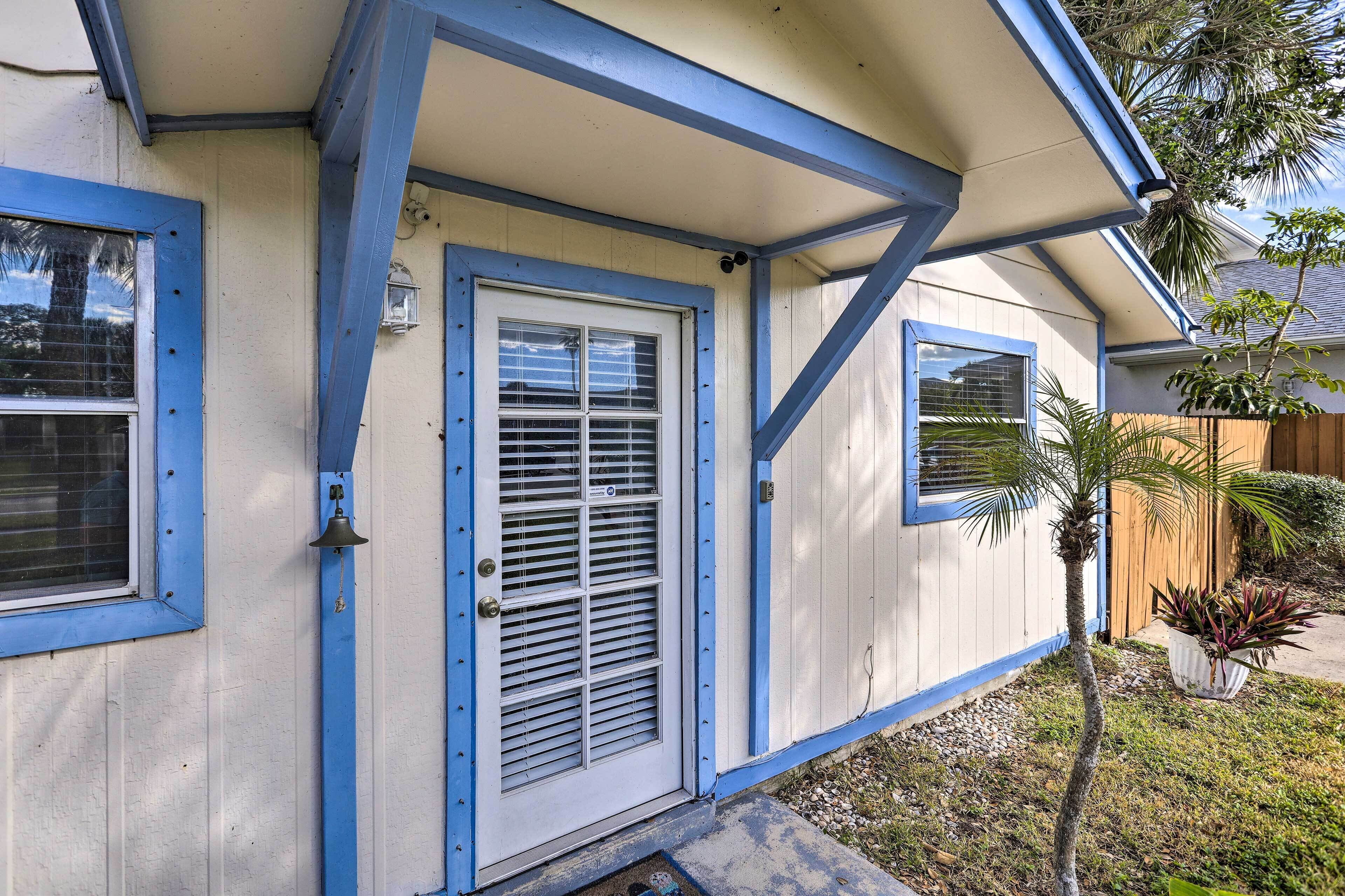 A house with a blue trim around the windows and door, a small porch, and a potted plant in the yard.