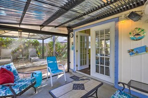 A covered patio with outdoor furniture, a clock, and a decorative plate on the wall. - Cape Canaveral Cottage w/ Hot Tub: Walk to Beach (Cape Canaveral)