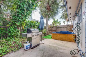 A backyard with a barbecue grill, a hot tub, and a wooden fence. - Cape Canaveral Cottage w/ Hot Tub: Walk to Beach (Cape Canaveral)