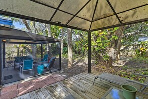 A covered outdoor area with a glass enclosure, wooden deck, and seating. - Cape Canaveral Cottage w/ Hot Tub: Walk to Beach (Cape Canaveral)