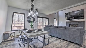 Una sala moderna con un sofá gris, una mesa de comedor con sillas y una chimenea.