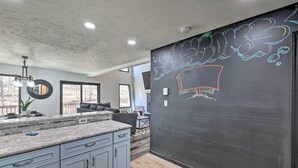 Una cocina moderna con encimeras de granito, gabinetes grises y una pared de pizarra con grafitis.