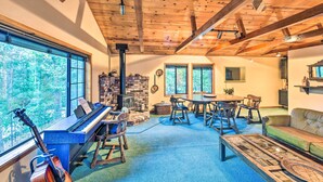 A cozy room with a piano, a guitar, a fireplace, a dining table, and a sofa.