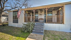 A single-story building with a porch, a flag, and a staircase leading to the entrance. - 'the Barn' Texas Wine Country Vacation Rental (Fredericksburg)