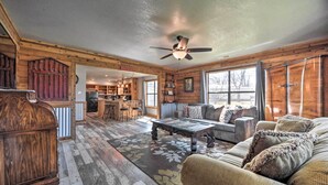 A rustic cabin interior with a wooden ceiling, a ceiling fan, a dining area, and a cozy seating area with a patterned rug. - 'the Barn' Texas Wine Country Vacation Rental (Fredericksburg)