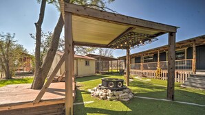 A covered outdoor area with a wooden pergola, a stone fire pit, and a fenced patio. - 'the Barn' Texas Wine Country Vacation Rental (Fredericksburg)