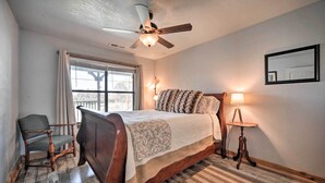 A bedroom with a wooden bed, a chair, a standing lamp, and a ceiling fan. - 'the Barn' Texas Wine Country Vacation Rental (Fredericksburg)