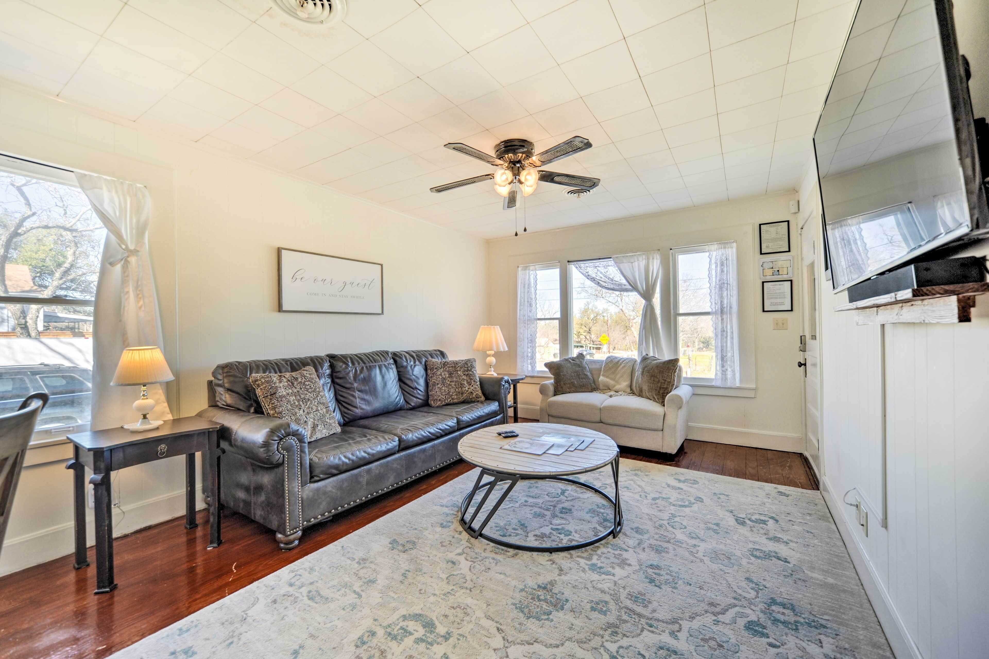 A living room with a leather sofa, a round coffee table, and a ceiling fan.