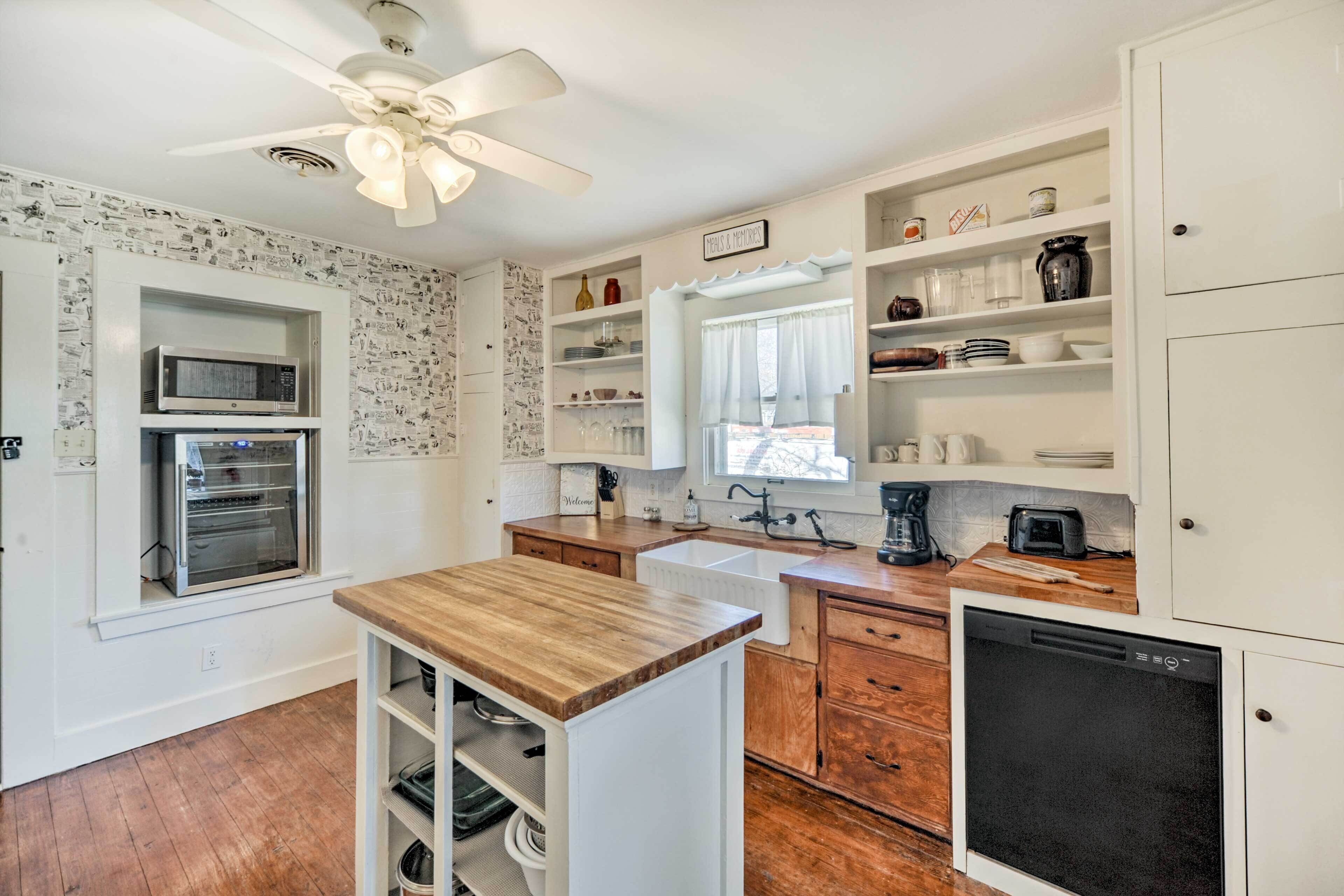 A modern kitchen with white cabinetry, a wooden countertop, a built-in oven, a dishwasher, and a ceiling fan.