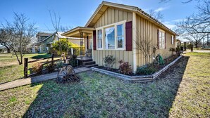 Ein eingeschossiges Haus mit Veranda, einem kleinen Garten und einem Holzzaun.