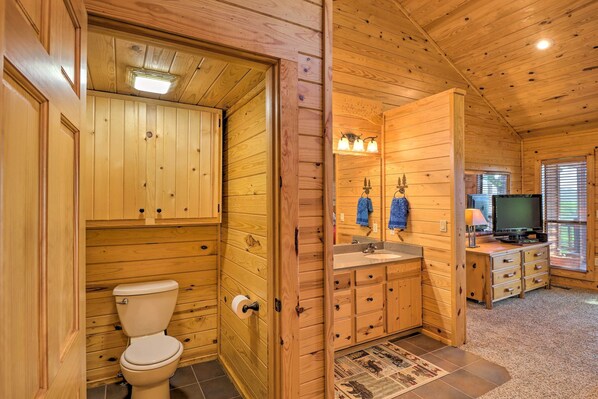 Baño de cabaña de madera con inodoro, lavamanos y armarios.