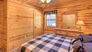 Ein Schlafzimmer in einer Holzhütte mit Bett, Schminktisch und Deckenventilator.