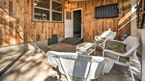 Un espace extérieur abrité, aménagé avec des meubles en osier, une porte et une fenêtre.