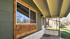 Une maison à l’extérieur vert, avec un cadre de fenêtre en bois et une base en briques.