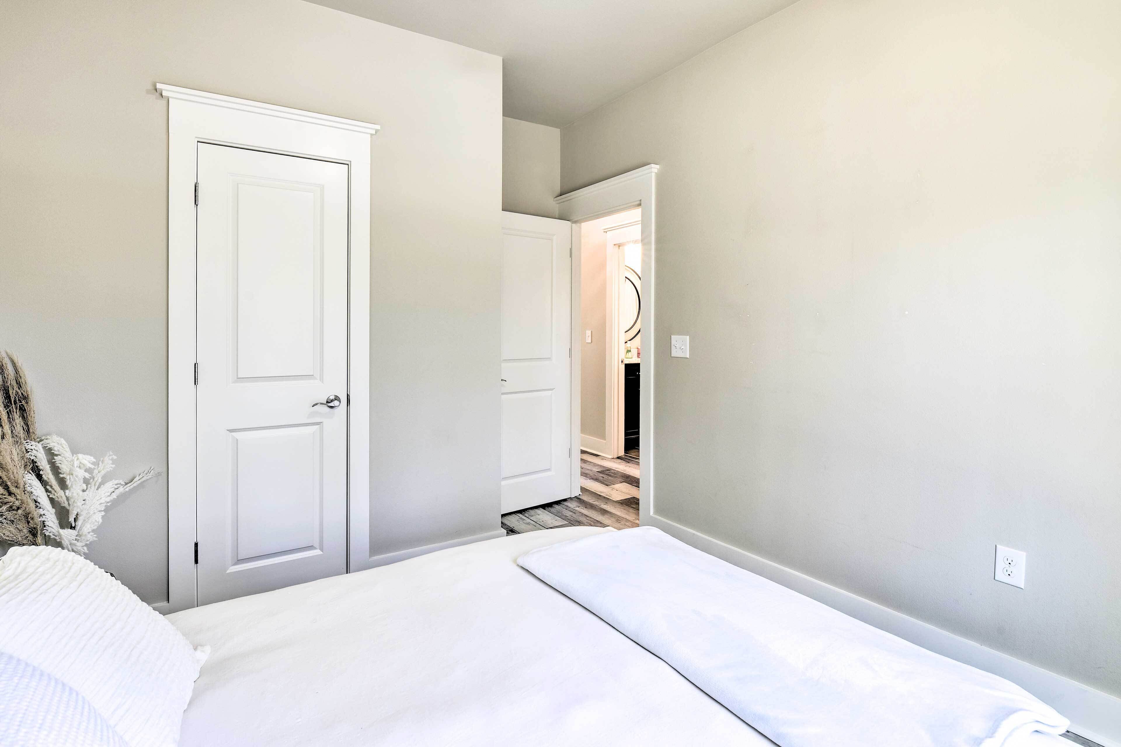 Une chambre à coucher comprenant un lit, une armoire et une porte donnant sur une autre pièce.