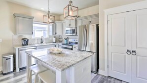A modern kitchen with white cabinetry, stainless steel appliances, and a marble island. - Modern Santa Rosa Beach Retreat w/ Yard & Patio! (Santa Rosa Beach)