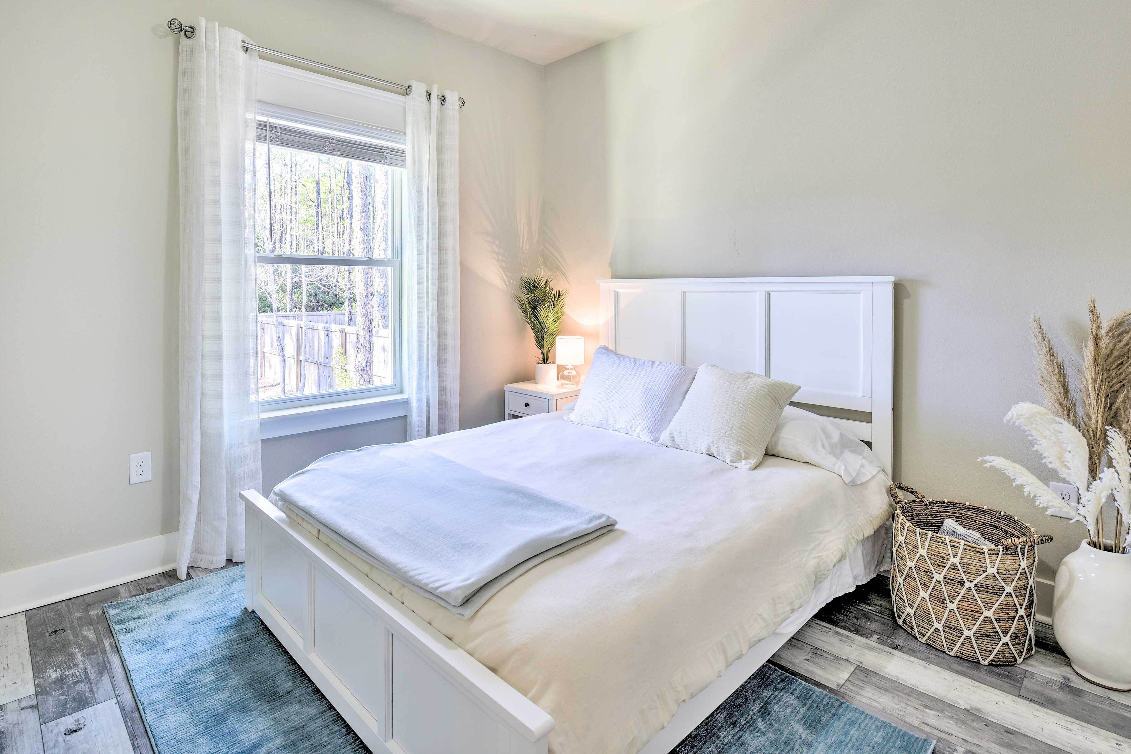 Une chambre à coucher avec un lit, une table de chevet, une fenêtre avec des rideaux et une plante sur la table de chevet.