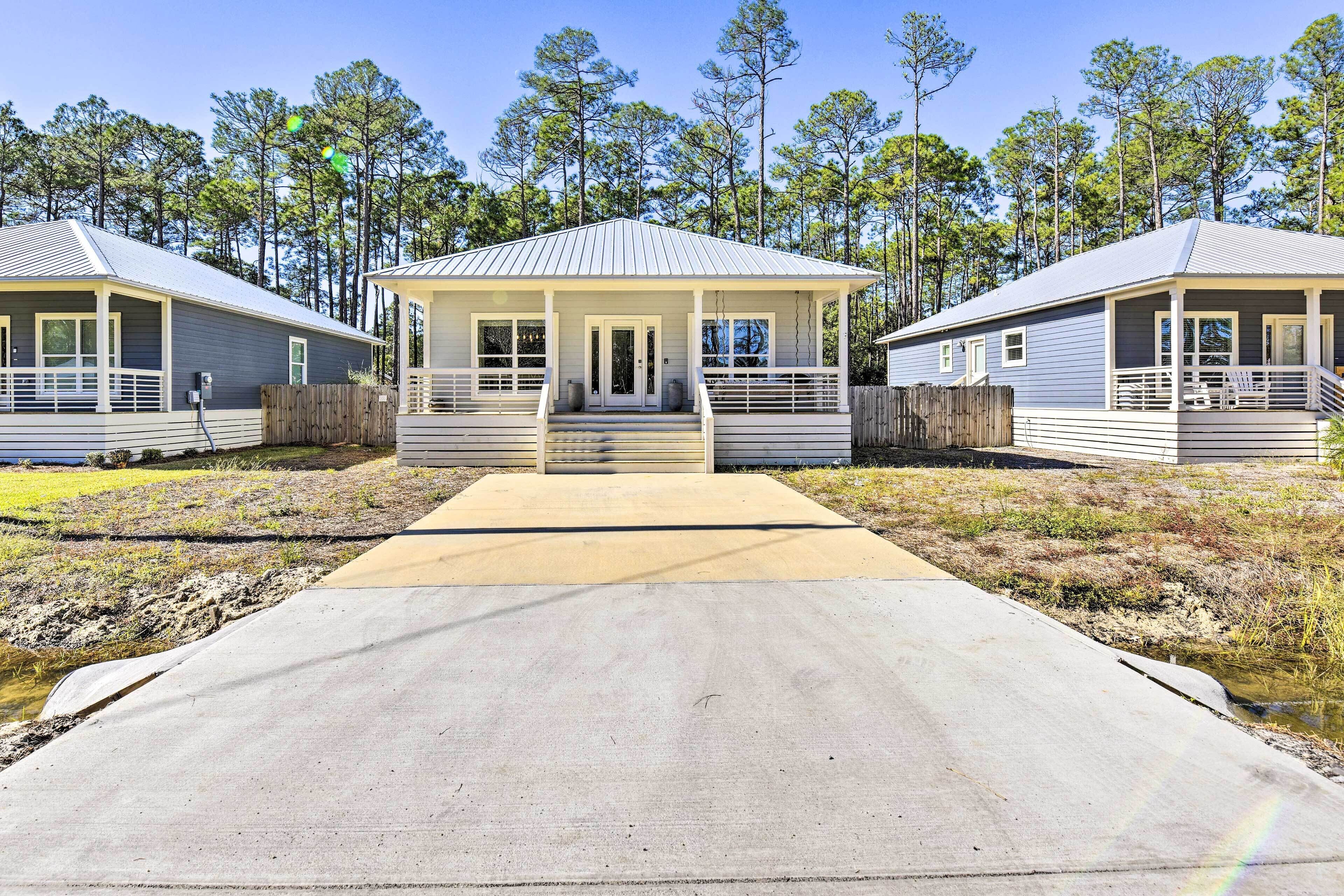 A two-story cabin with a covered porch and a concrete pathway leading to the entrance.