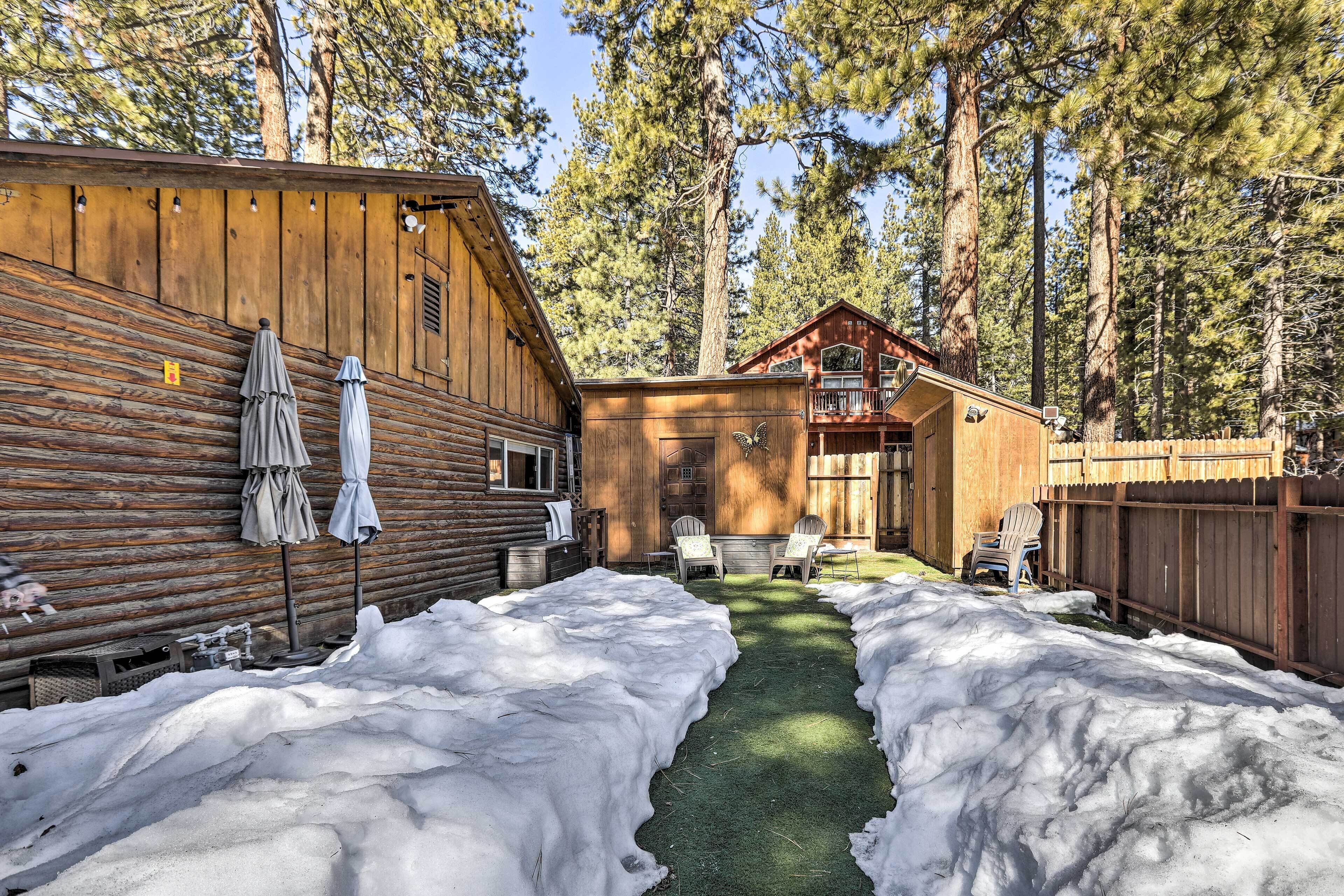 A log cabin with a wooden exterior, a covered patio area, and a snow-covered yard.