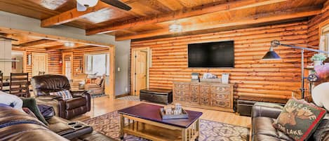 A spacious living room with leather sofas, a coffee table, and a ceiling fan.