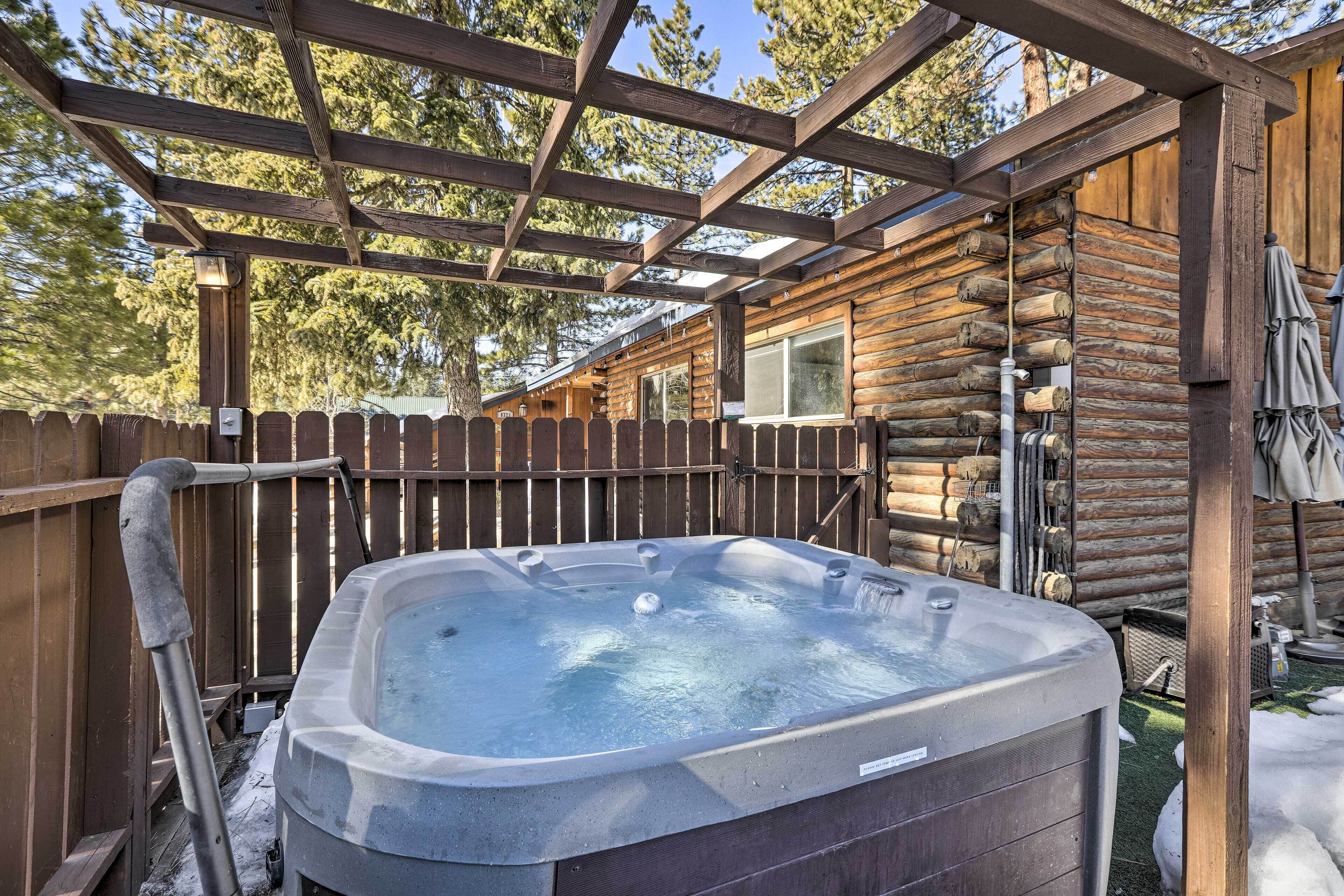 A hot tub in a wooden cabin with a wooden deck and a pergola overhead.