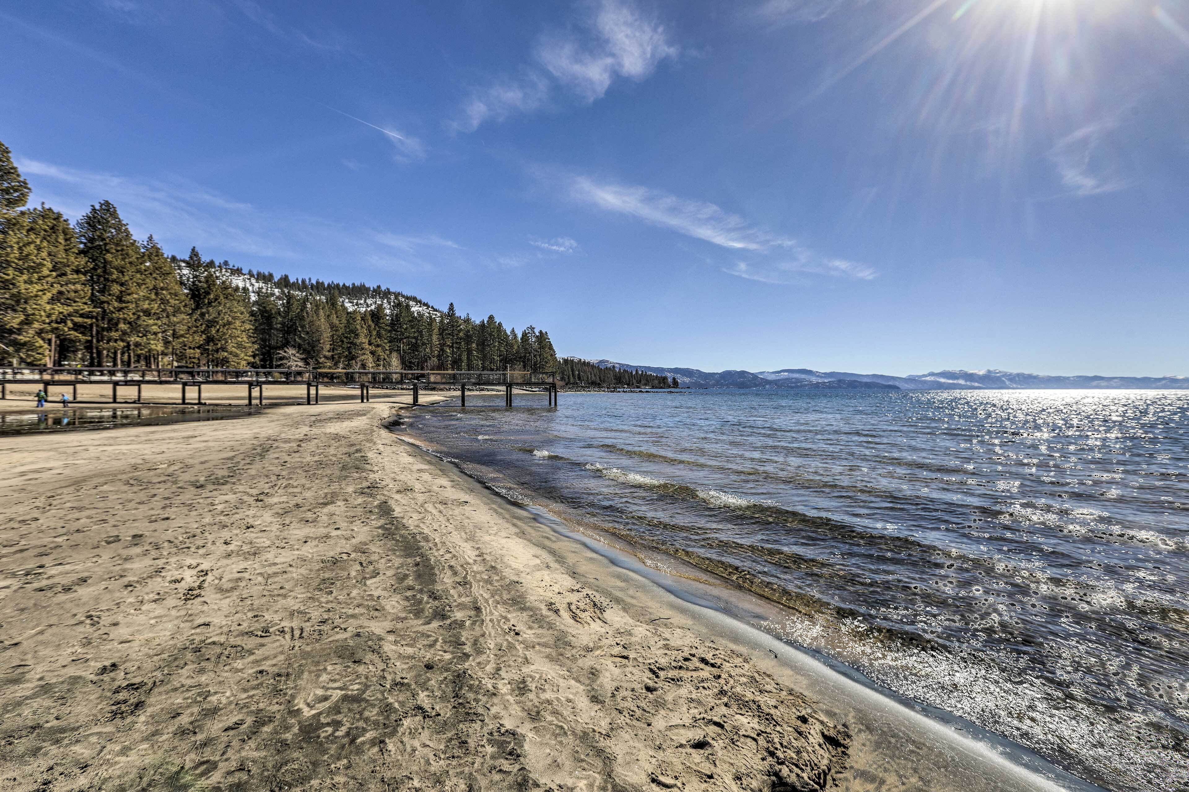 A beach with a wooden walkway and a forested hillside in the background.