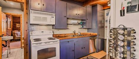 A kitchen with a stove, microwave, sink, and cabinets.