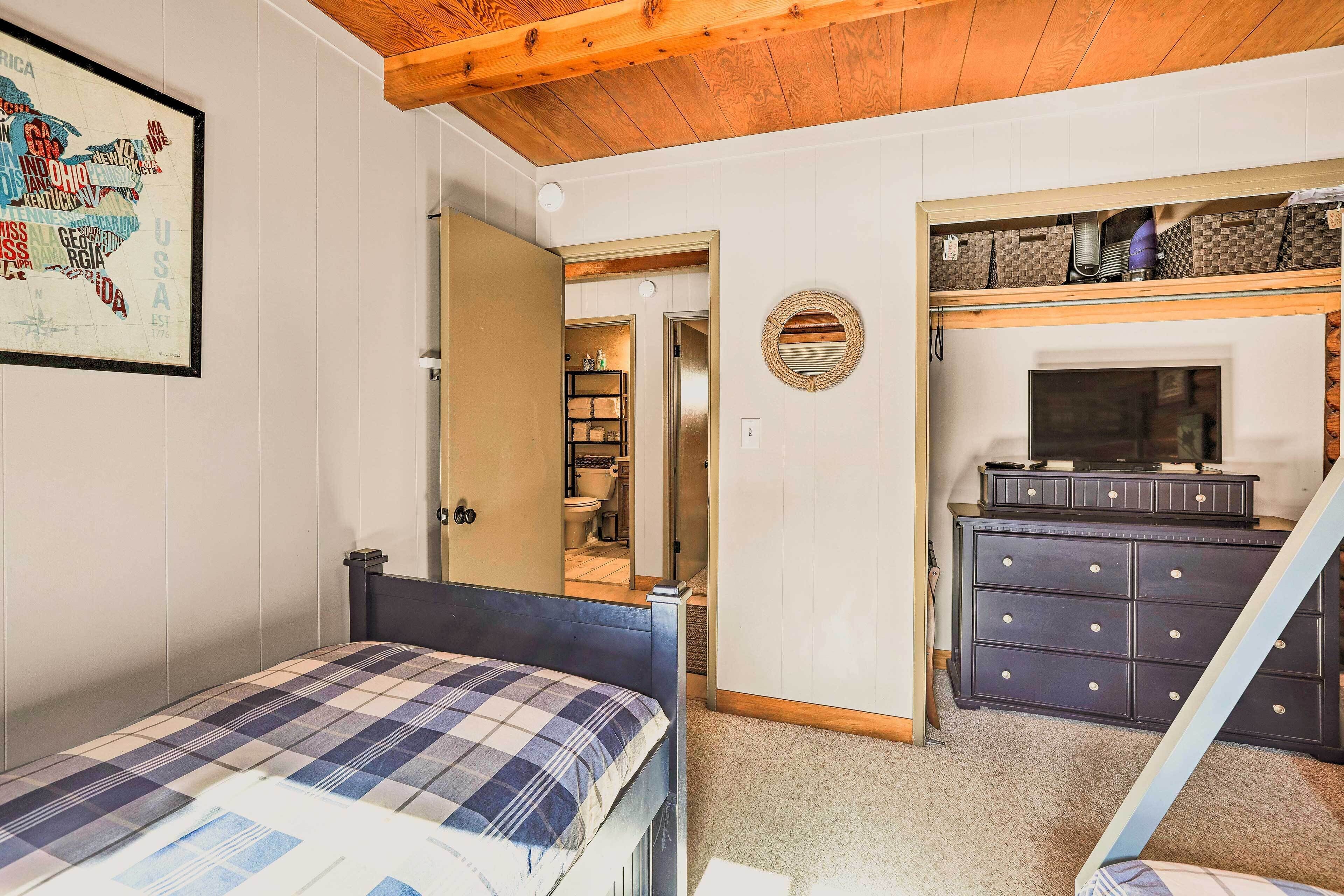 Un dormitorio con una cama, un aparador, un televisor y un mapa en la pared.