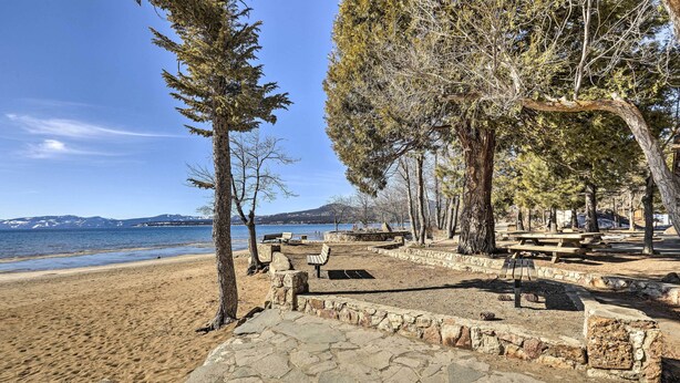 A beachside park with stone pathways, picnic tables, and benches.