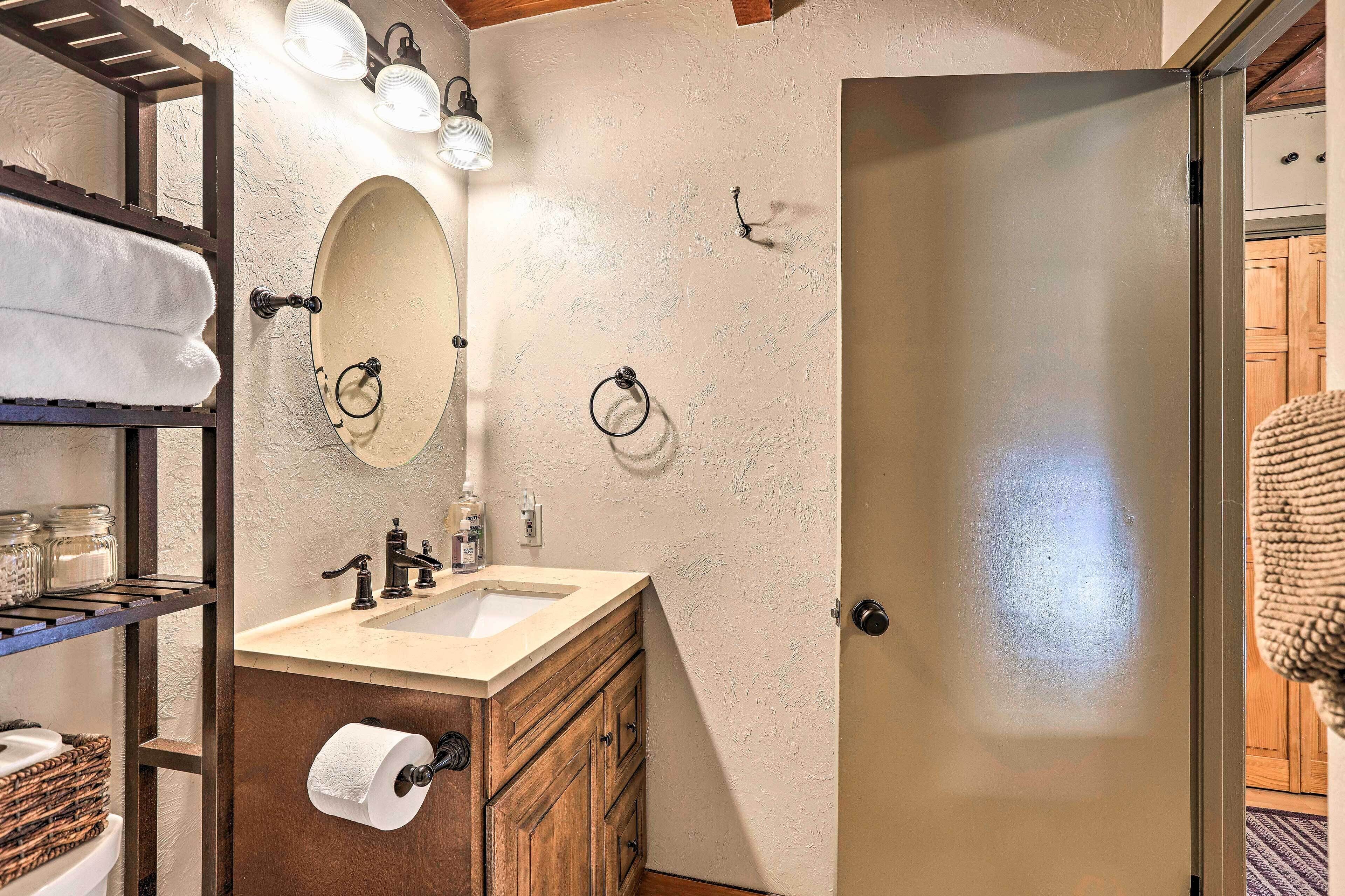 A bathroom with a wooden vanity, a sink, a mirror, and a towel rack.