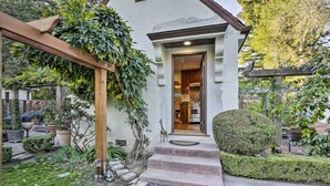Una casa con una pérgola de madera, un jardín bien cuidado y una zona de cocina visible.