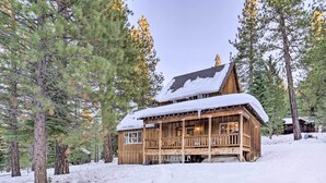 Eine Holzhütte mit Veranda, umgeben von Schnee und Kiefern.