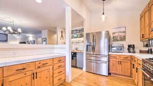 Une cuisine moderne avec des meubles en bois, des appareils en acier inoxydable et un plan de travail blanc.