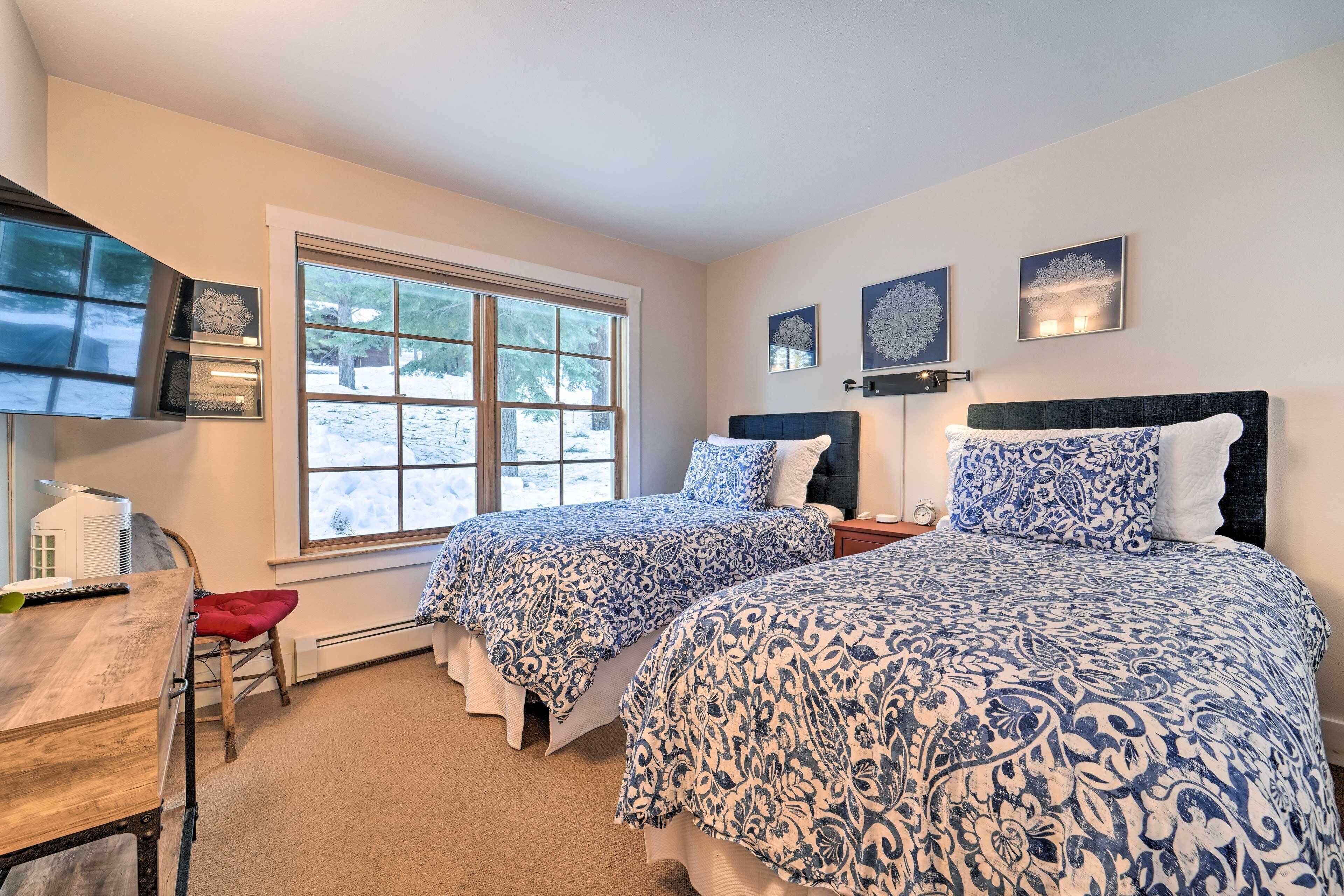 A bedroom with two beds, a desk, and a window.