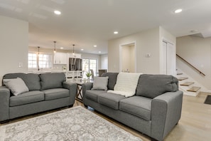 Relax in this stylish living room with two sofas, a patterned rug, and a staircase leading to an upper level.
