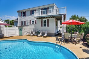 Une maison à deux étages avec une piscine, un balcon et du mobilier d’extérieur.