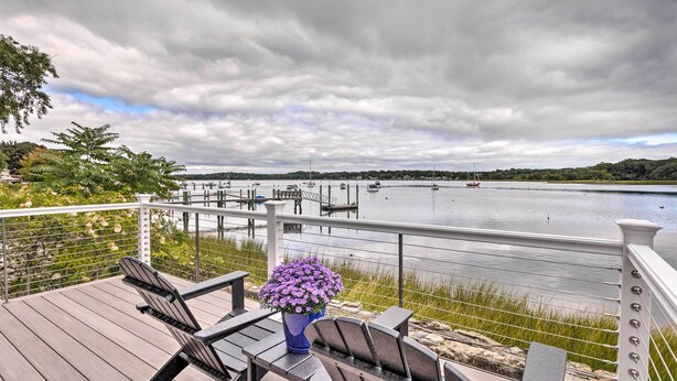 A deck with chairs and a table, overlooking a calm river with boats and docks. - Charming Bristol Cottage w/ Private Beach! (Bristol)