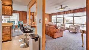 A spacious living area with a brown sofa, patterned chairs, and a large window offering a view. - Rhode Island Oceanview Retreat: Walk to Shore! (Narragansett)