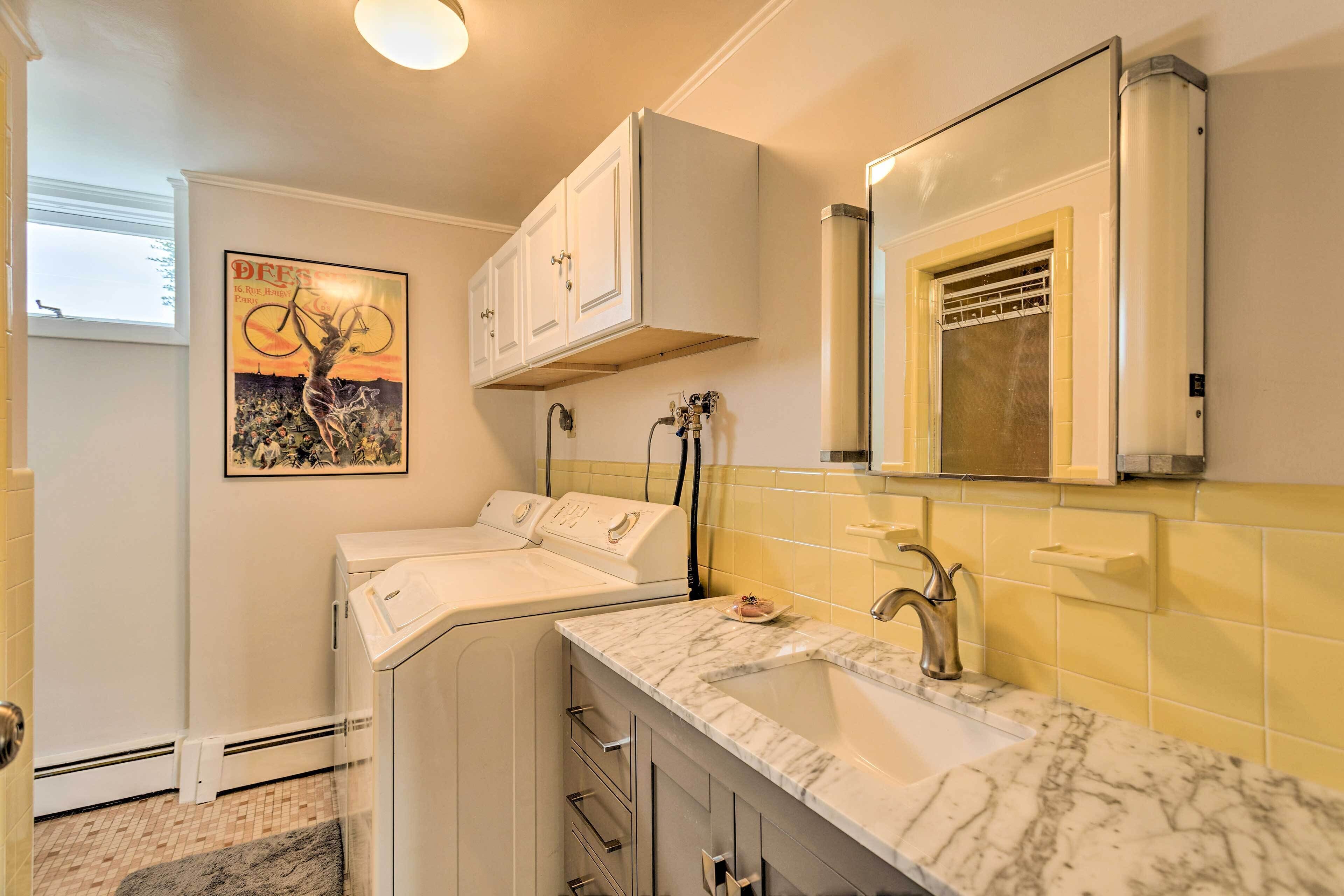 Une salle de bain moderne avec un lavabo en marbre, un grand miroir et une affiche accrochée au mur.