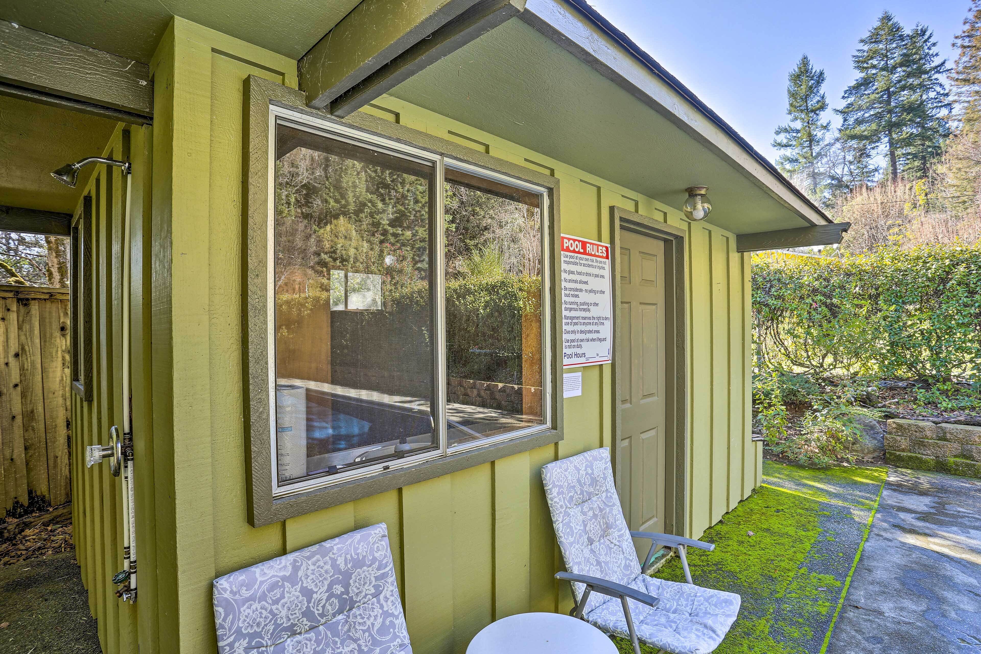 A poolside area with a sign detailing pool rules, a window, and a chair.
