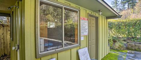 A poolside area with a sign detailing pool rules, a window, and a chair.