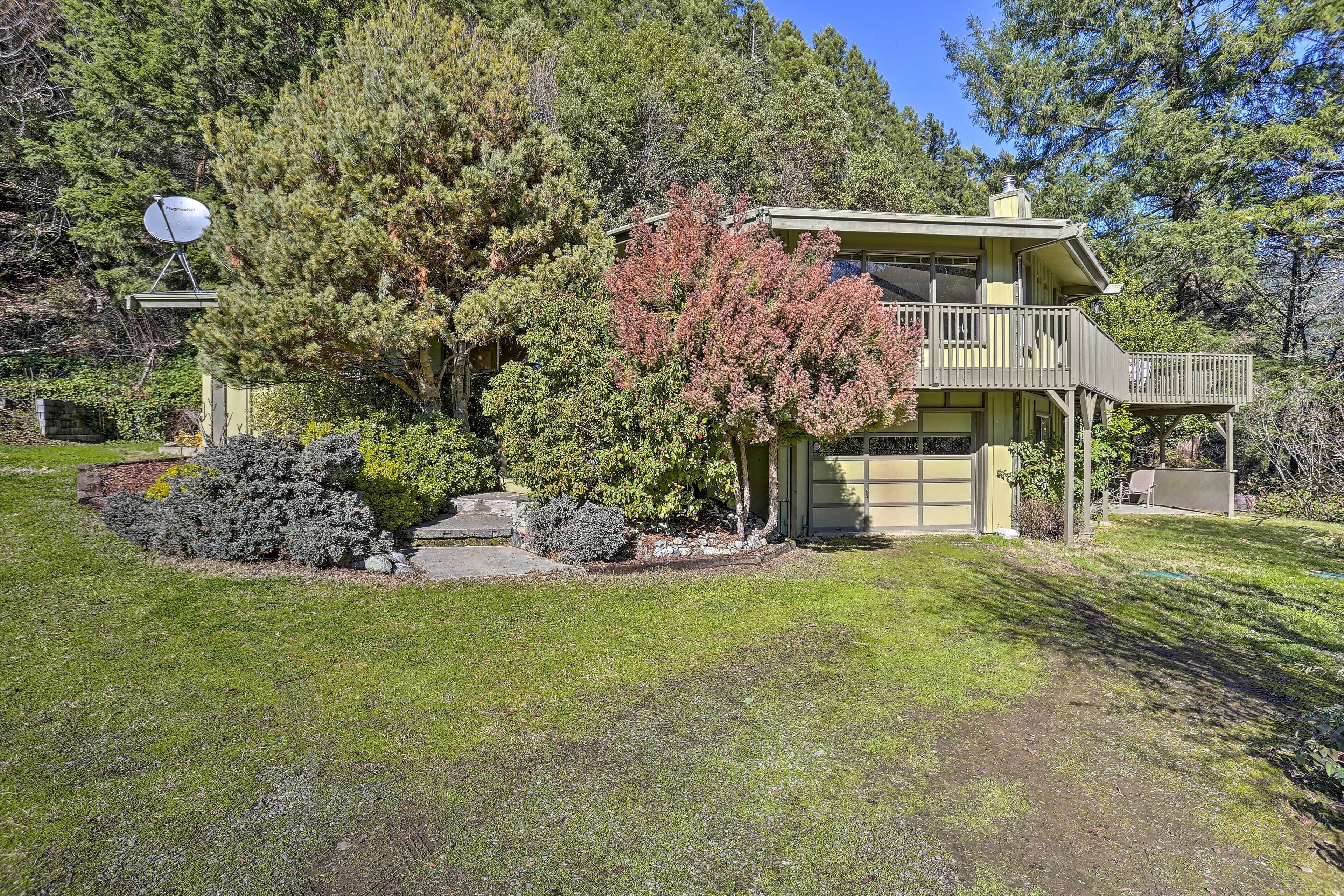 A two-story house with a balcony, surrounded by trees and a satellite dish.