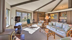 A cozy living room with a fireplace, comfortable seating, and a bookshelf. - Woodsy Willow Creek Getaway w/ Pool & Deck! (Willow Creek)