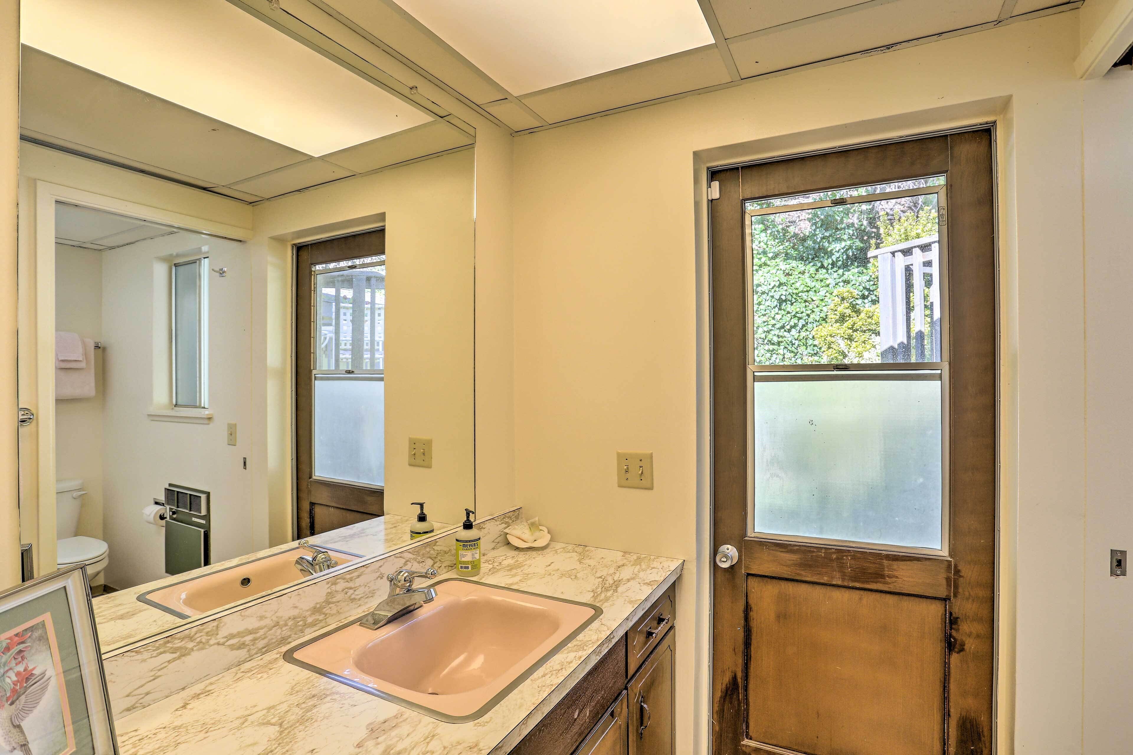 A bathroom with a marble sink, a large mirror, and a door with a frosted window.