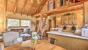 A wooden interior with a dining area, kitchen, and a loft space. - Walk to Grand Lake: Historic Dtwn Cabin! (Grand Lake)